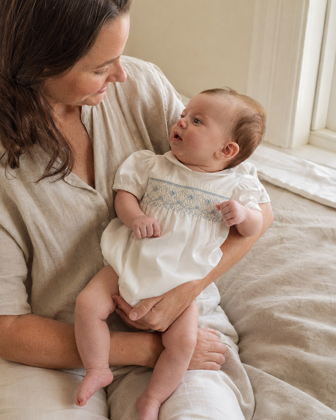 Newborn wearing a soft ivory embroidered heirloom romper