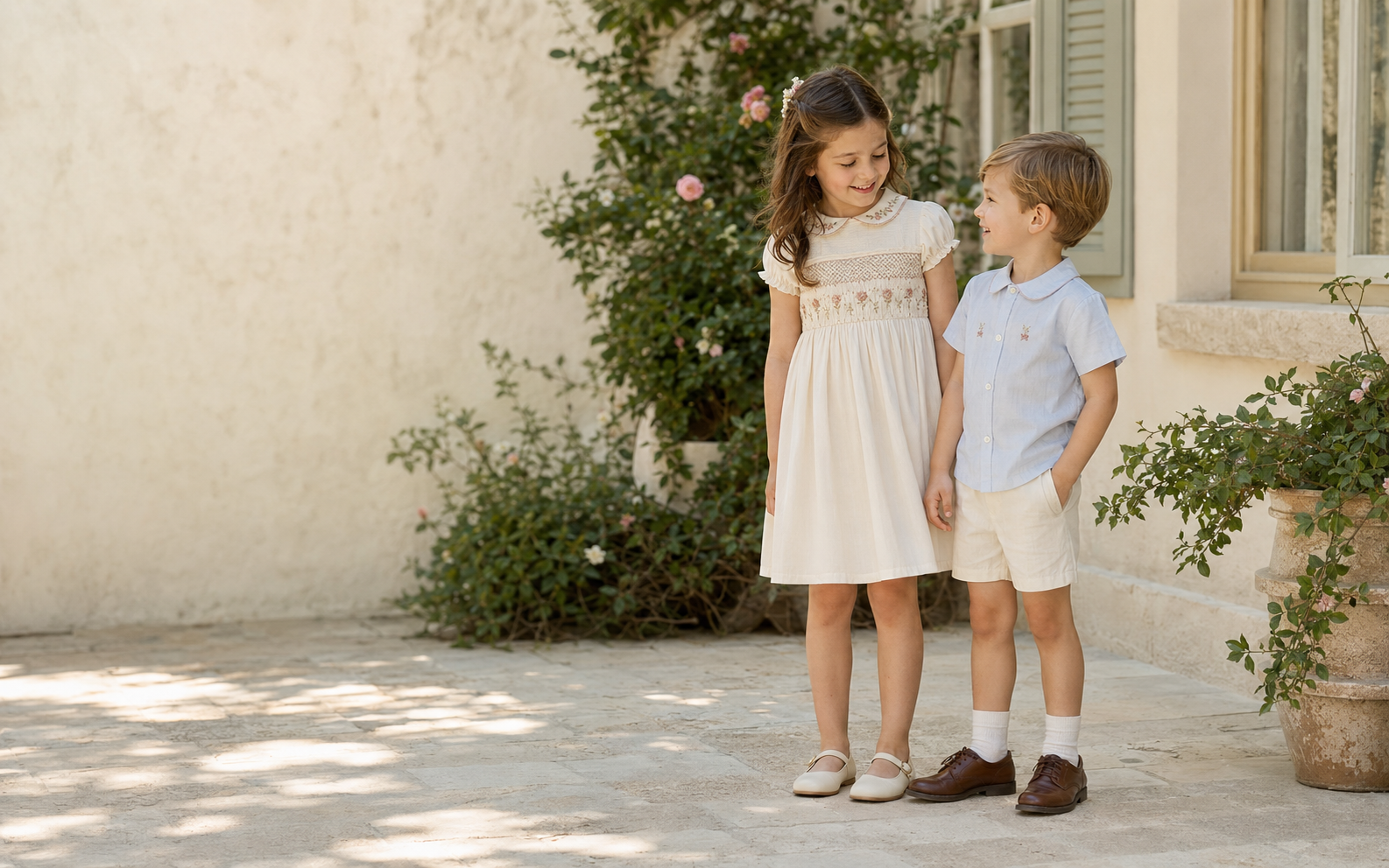A girl and boy wearing timeless embroidered TivaBella clothing in a sunlit garden